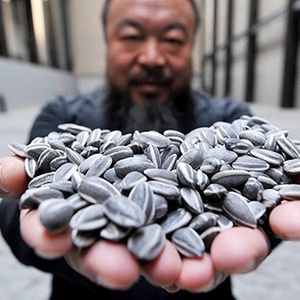 O artista chinês Ai Weiwei com algumas das sementes de porcelana da obra Sunflower Seeds