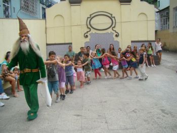 Ator fantasiado de duende acompanhado de diversas crianças