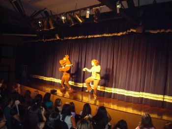 Dois atores no palco caracterizados como personagens do desenho Scooby-Doo